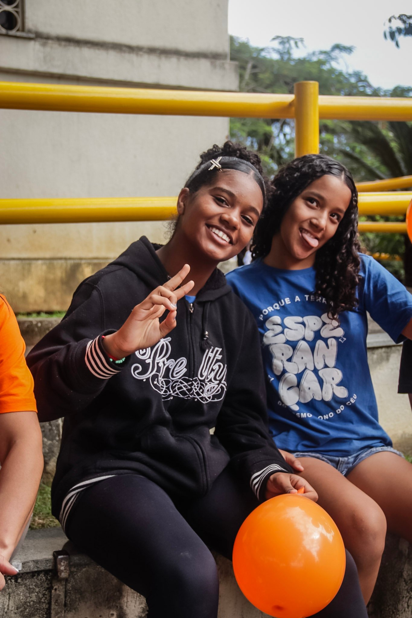 Duas adolescentes do Instituto Alfa sorrindo com um balão laranja