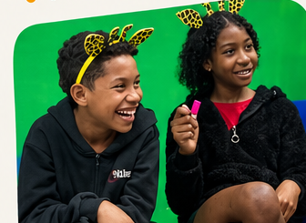 Duas crianças do Capaz Kids sorrindo, com tiaras de girafa